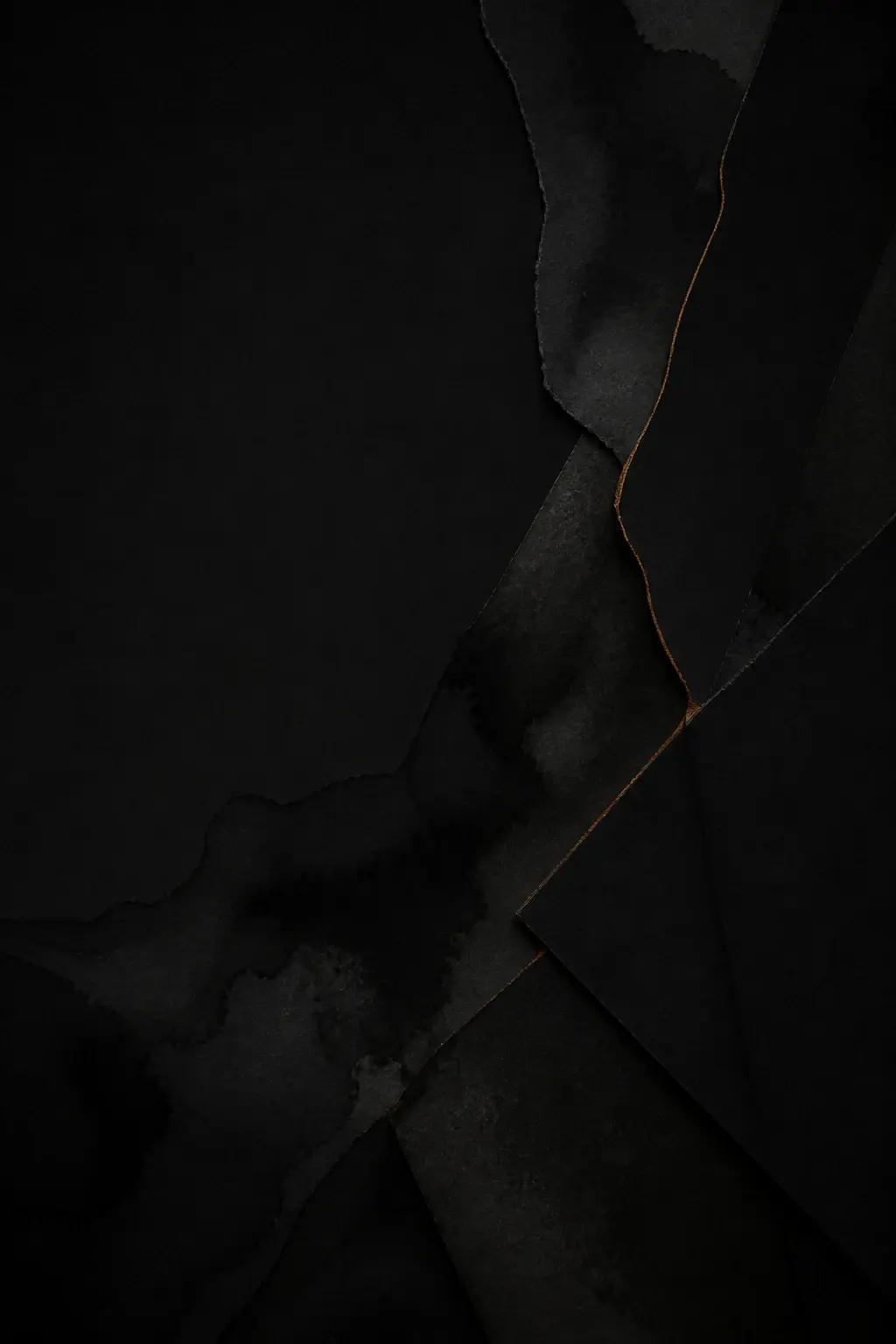 Layered matte-black paper forms joined by a fine amber seam